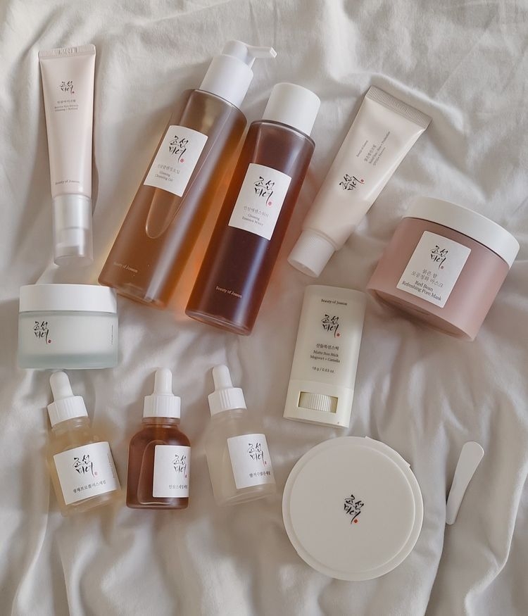 Beauty of Joseon skincare routine collection including serums, sunscreens, Ginseng Essence Water, and Red Bean Refreshing Pore Mask on white fabric.
