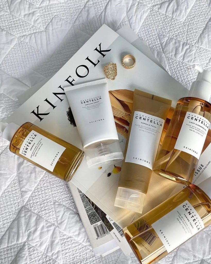 KIN1004 Madagascar Centella skincare set featuring ampoule, toner, soothing cream, and cleanser laid out on Kinfolk magazine.